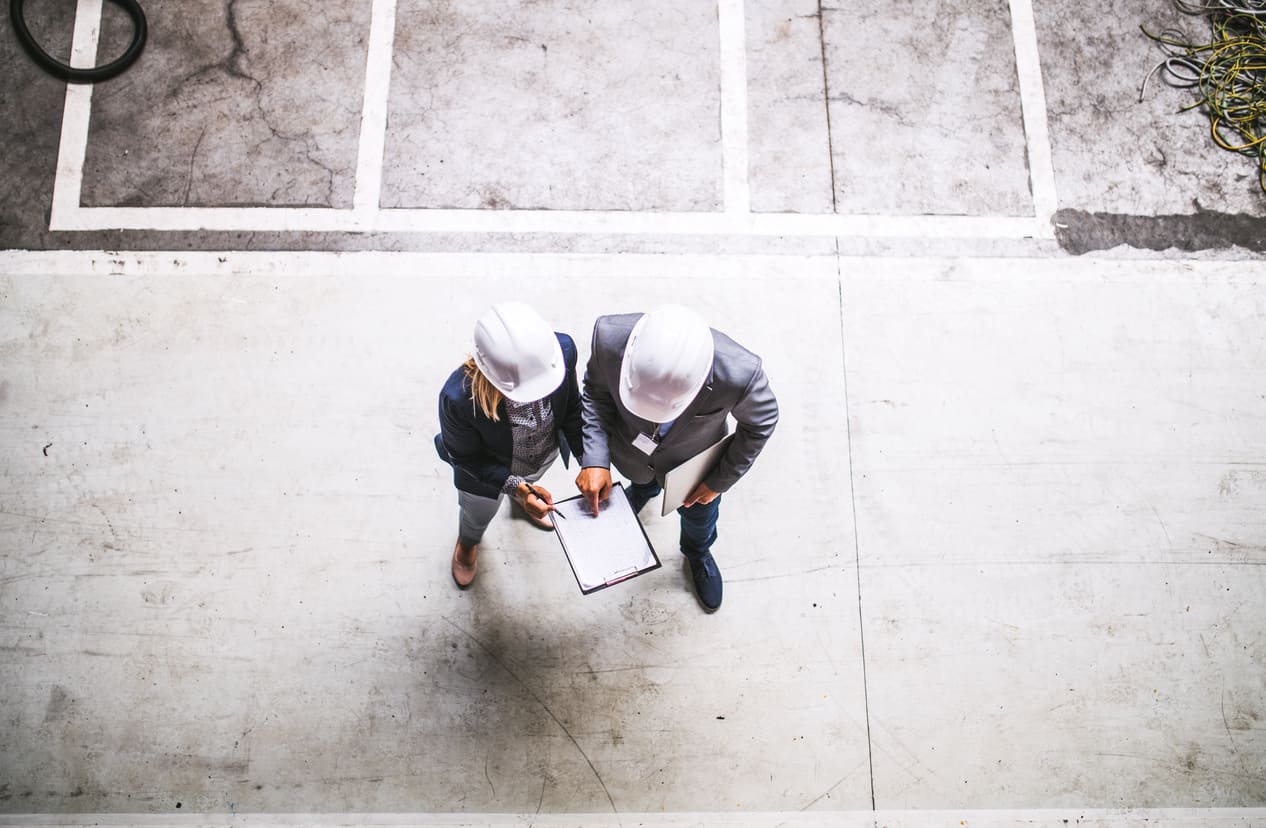 A top view of an industrial man and woman engineer with clipboard in a factory