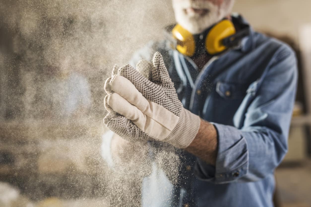 Carpenter shaking dust off gloves